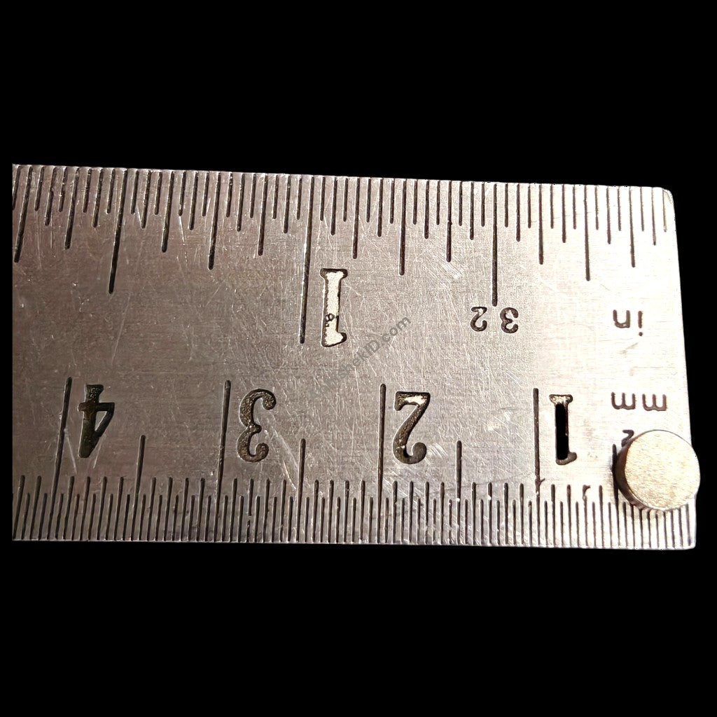 Single 5mm diameter neodymium round magnet on steel ruler showing exact size