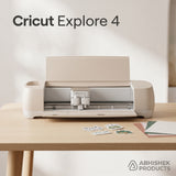 Beige Cricut Explore 4 Smart Cutting Machine on a wooden desk with paper sheets for custom sticker making.