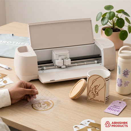 Cream Cricut Explore 4 Smart Cutting Machine crafting gold vinyl decals to personalize ceramic mugs and tags.