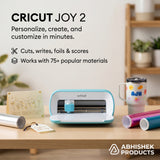 Blue Cricut Joy 2 machine with vinyl rolls, creating custom cardstock greeting cards and personalized tumbler decals.