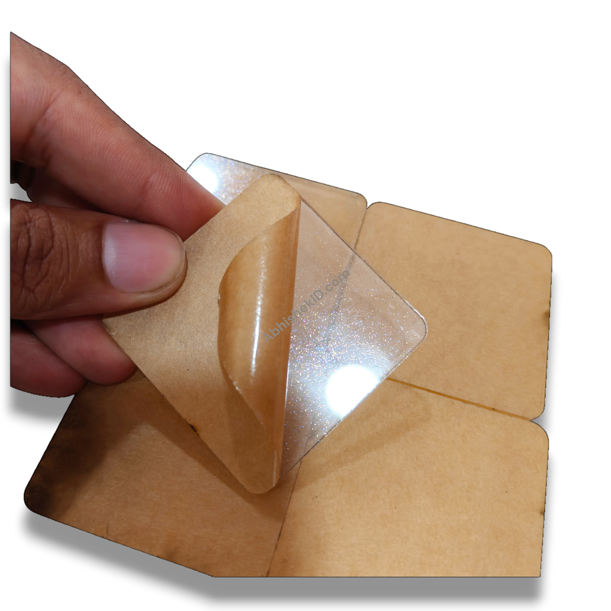 49mm acrylic puzzle DIY tiles, 2mm clear adhesive sparkle gumming square round-corner puzzle pieces, being peeled.